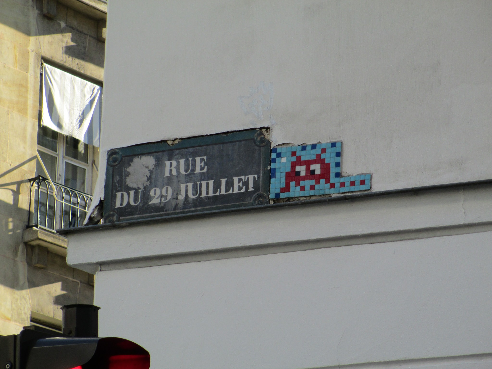 Red space invader mosaic next to the road sign for Rue de 29 Juillet